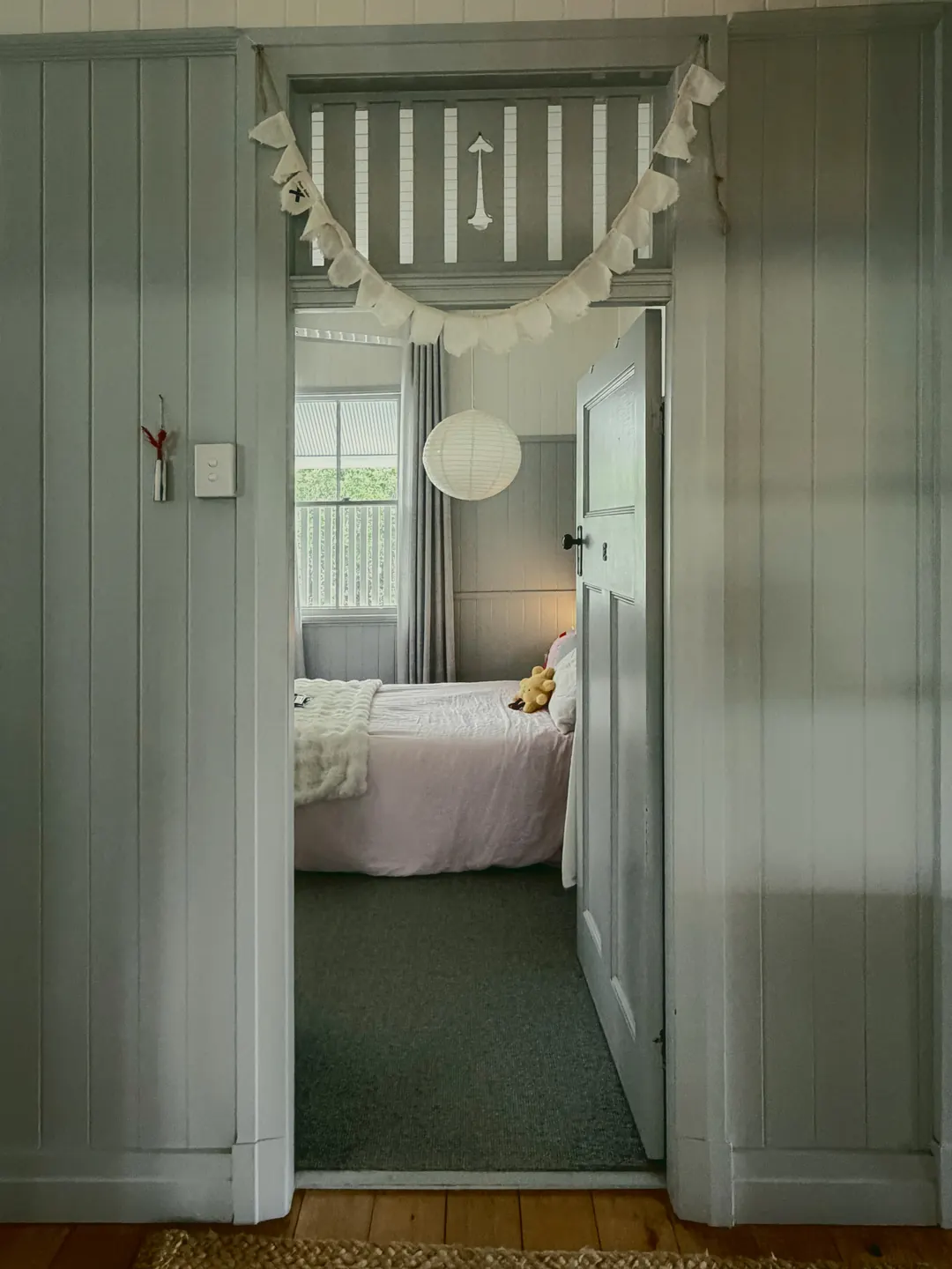 A bedroom glimpsed through a VJ doorway with fretwork above it