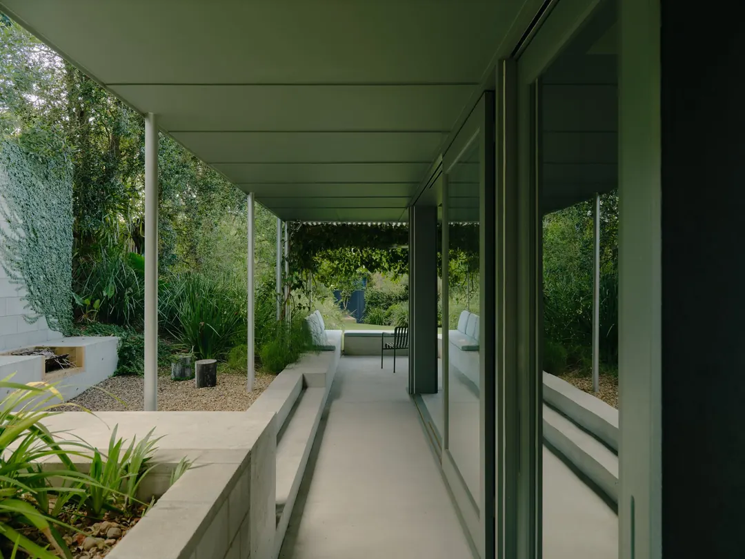 Concrete breezeway path lined with grasses and a planter bed