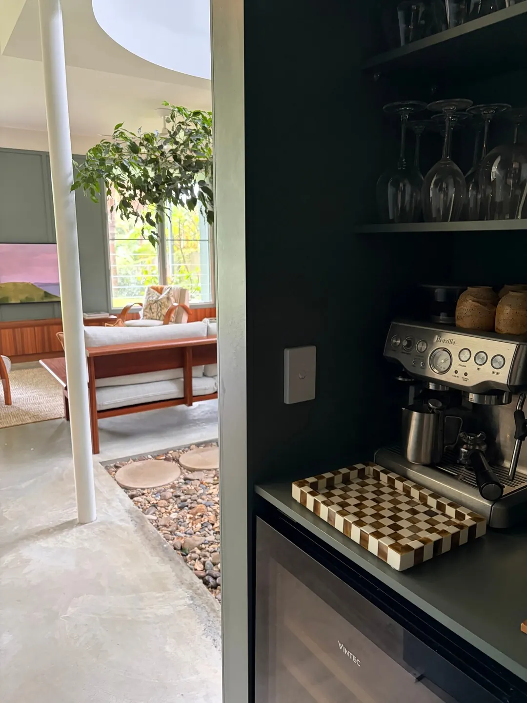 Coffee bar in bottle-green joinery, looking through to the indoor garden and lounge