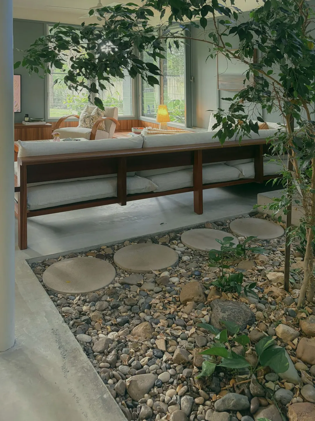 Indoor garden of river stones and a small tree beside the lounge