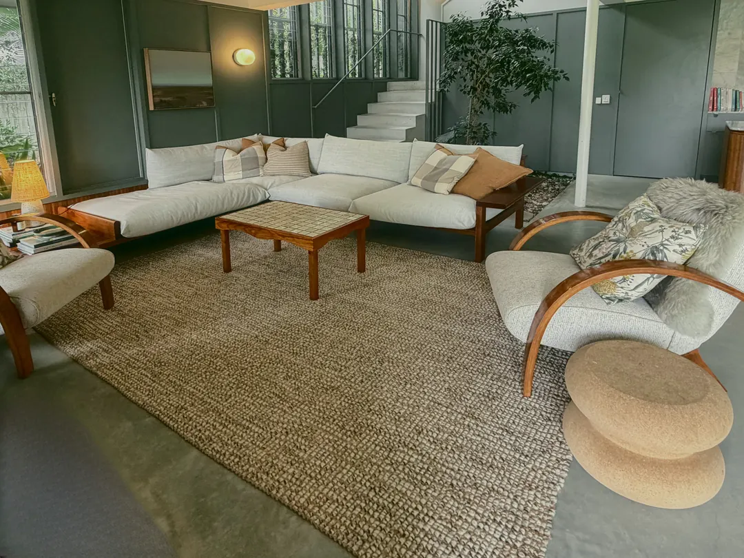 A white sofa and bentwood chairs on a jute rug beside the indoor garden