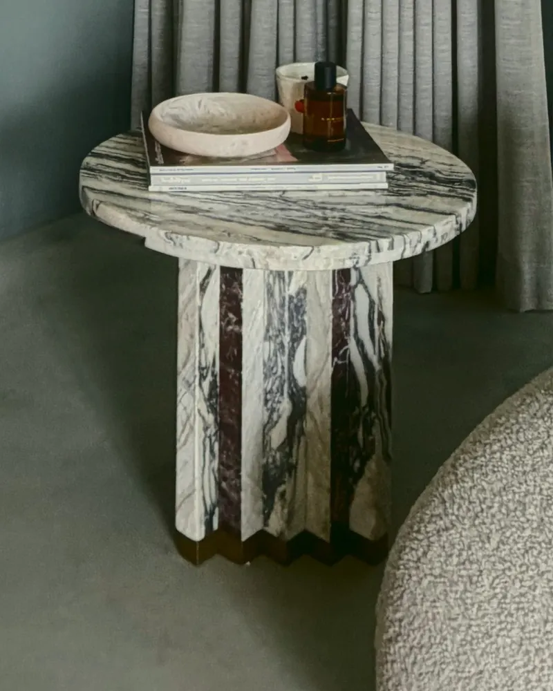 A round marble side table with a fluted base